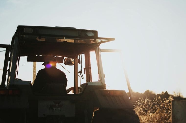 Bonde på traktor i solnedgang